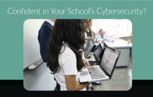 Students holding laptops at the front of a classroom.